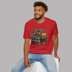 A man wearing a red graphic t-shirt with a vintage Chevy Girl 1955 truck design, paired with light blue jeans, sitting on a white block against a solid gray background.