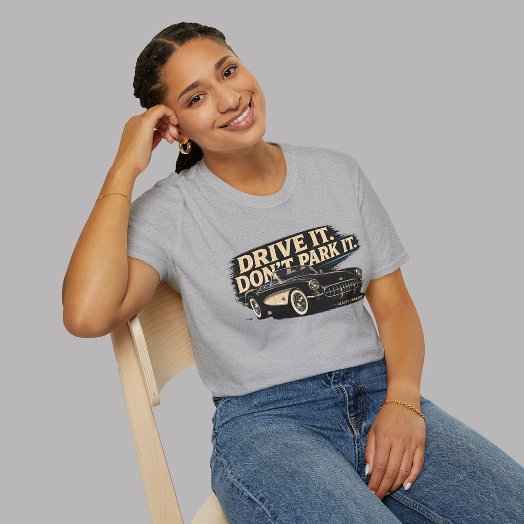 Woman wearing a gray t-shirt with a vintage car graphic and text, sitting on a chair against a plain background