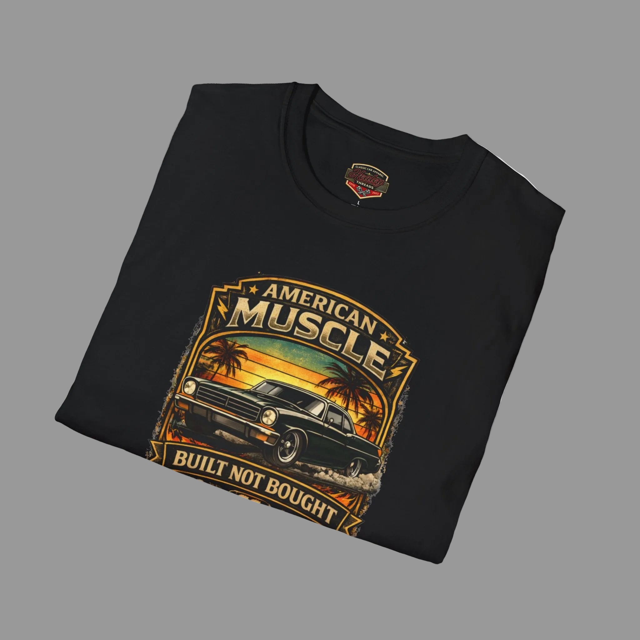 Folded black t-shirt with 'American Muscle' car graphic design on a gray background