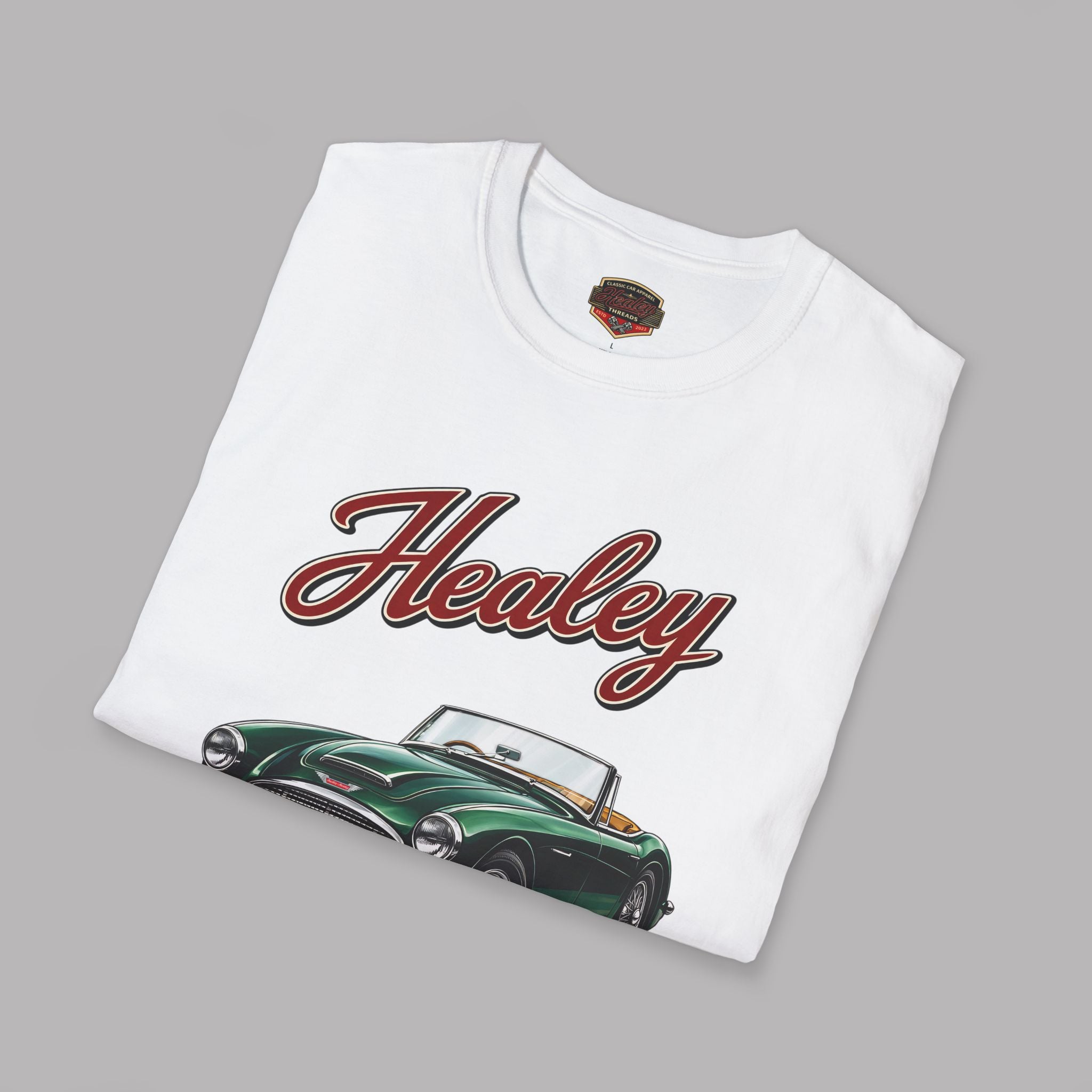Folded white t-shirt with a classic 'Healey' car design on a gray background