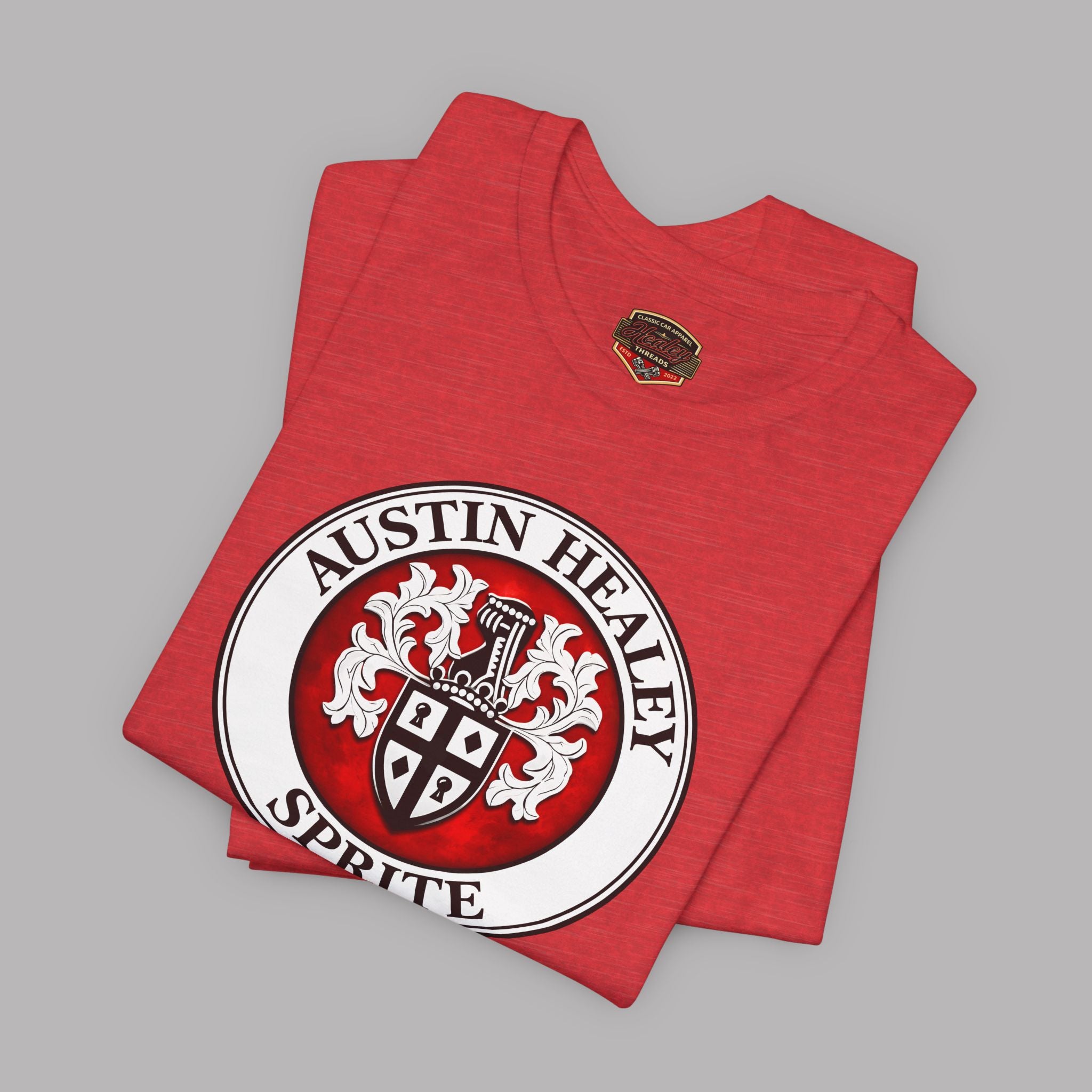Folded heather red t-shirt with Austin Healey Sprite logo on a gray background