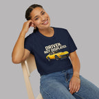 Woman wearing a navy blue t-shirt with a yellow muscle car graphic and text, sitting on a chair against a gray background