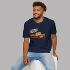Man wearing a navy blue t-shirt with a graphic and text, sitting on a white stool against a gray background.