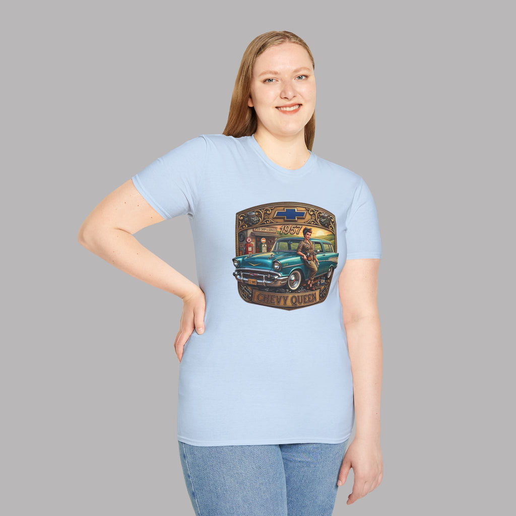A woman modeling a light blue crewneck t-shirt with a vintage graphic of a teal car and a gold-colored badge. She is wearing blue jeans against a solid gray background.