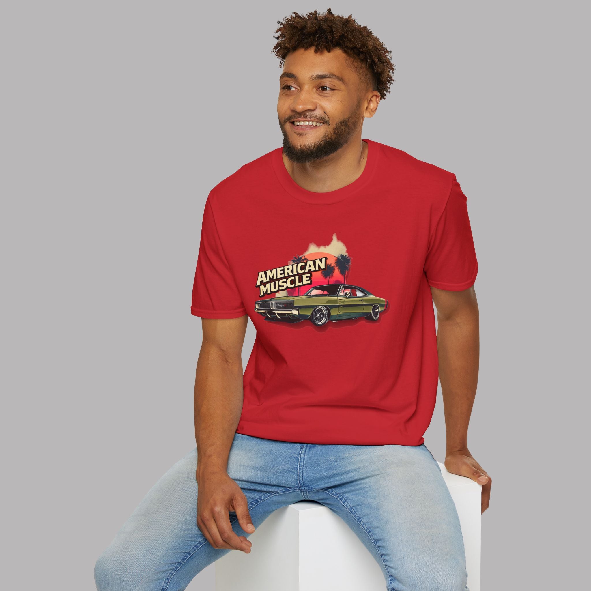 Man wearing a red t-shirt with 'American Muscle' graphic sitting on a white stool against a gray background