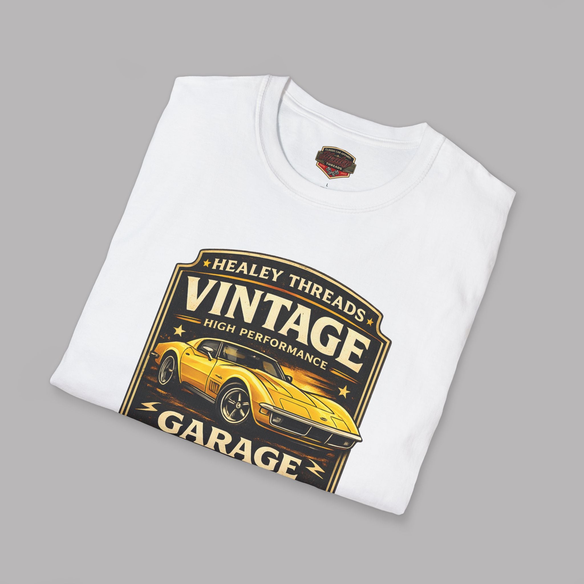 Folded white t-shirt with 'Healey Threads Vintage Garage' graphic on a gray background