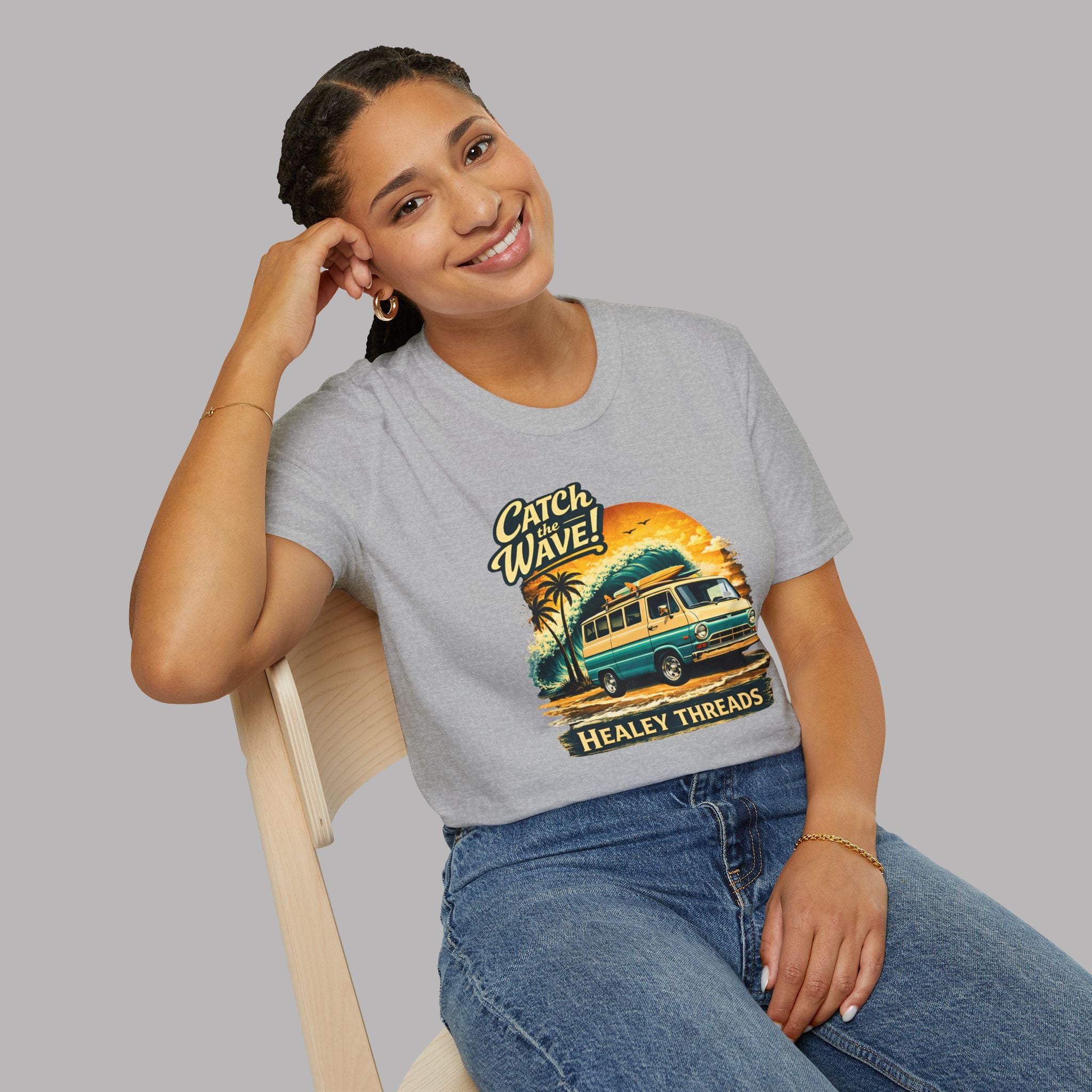 Woman wearing a sport gray t-shirt with a graphic classic van design sitting on a chair against a plain background