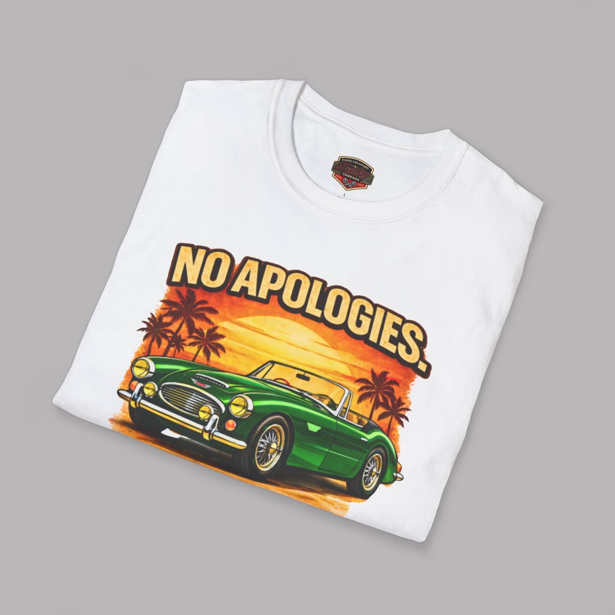 Folded white t-shirt with a green Healey car graphic and 'NO APOLOGIES' text on a gray background