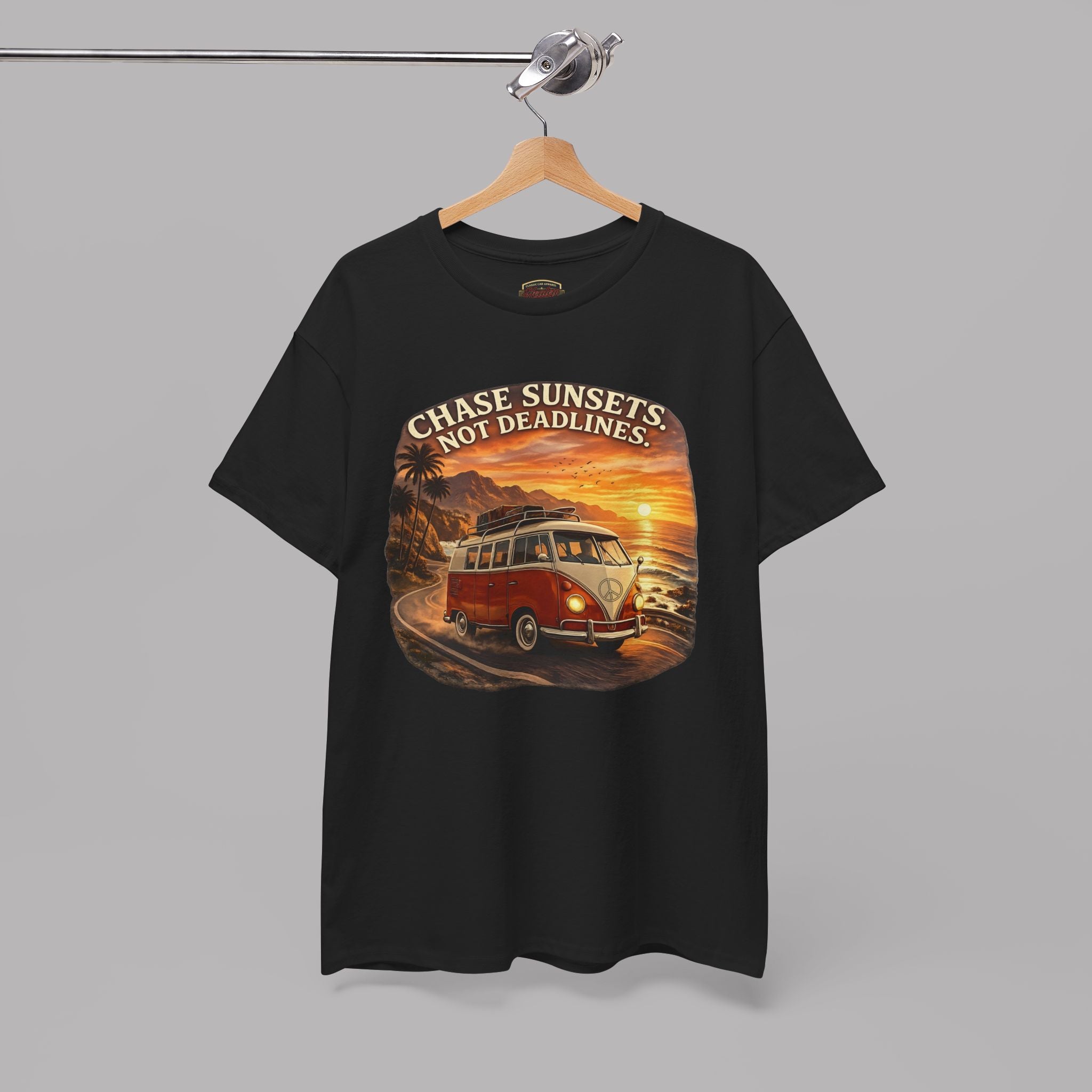 Black t-shirt with a graphic design of a classic van and sunset text on a hanger against a gray background