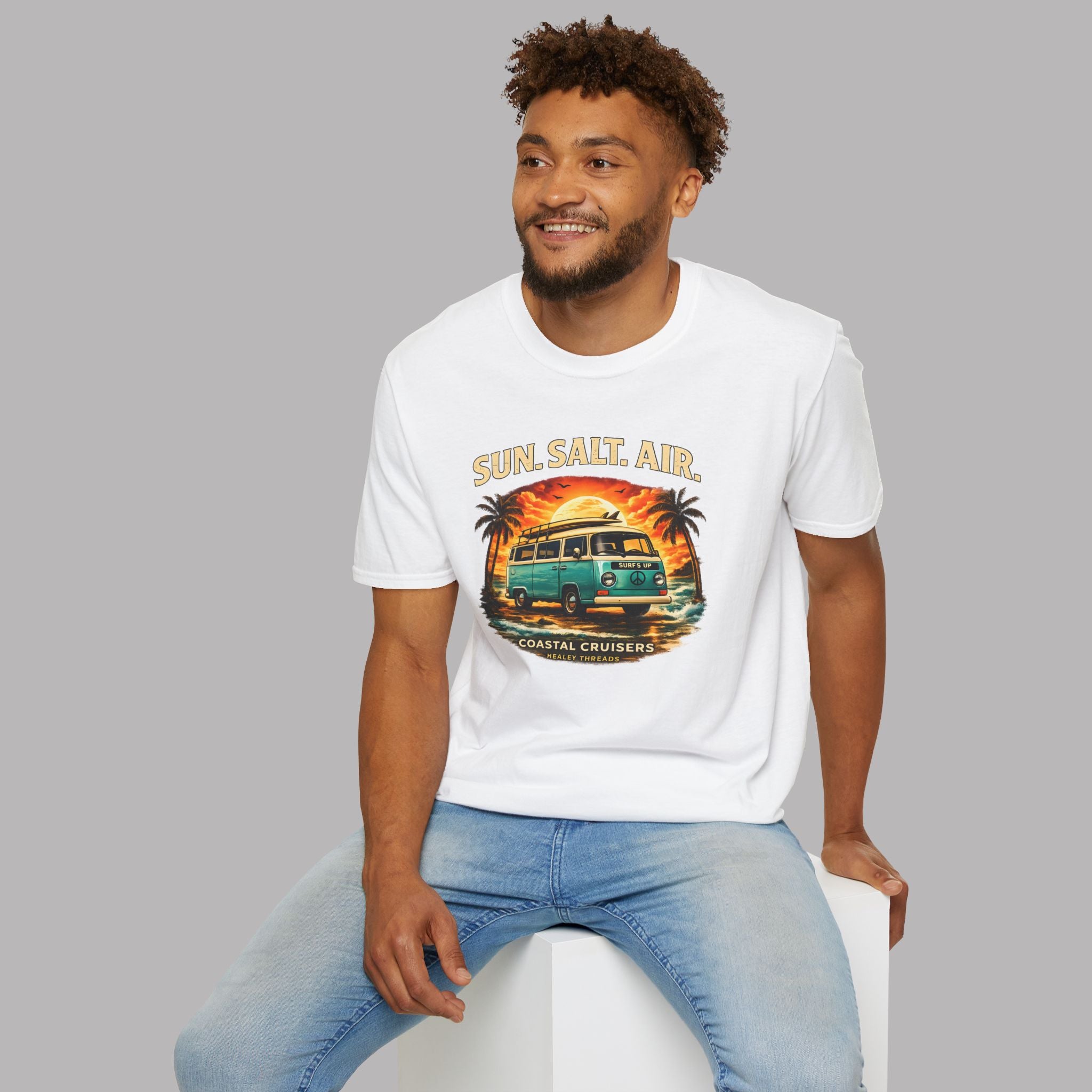 Man wearing a white t-shirt with a classic van graphic design sitting on a white stool against a gray background