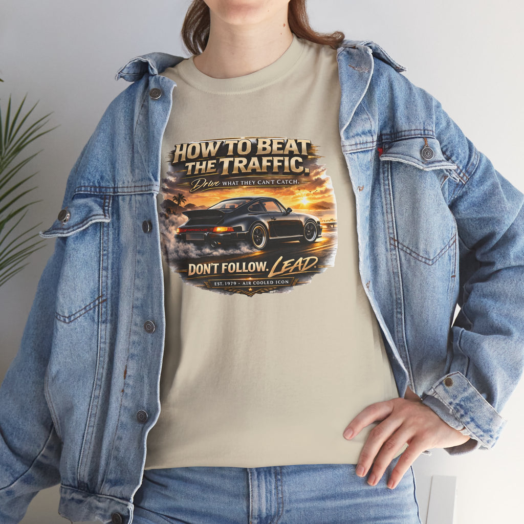 Person wearing a sand t-shirt with a classic car graphic design and text, standing indoors.