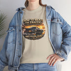 Person wearing a sand t-shirt with a classic car graphic design and text, standing indoors.