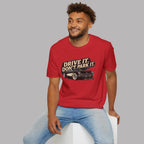 Man wearing a red t-shirt with a vintage car graphic and text, sitting on a white stool against a gray background