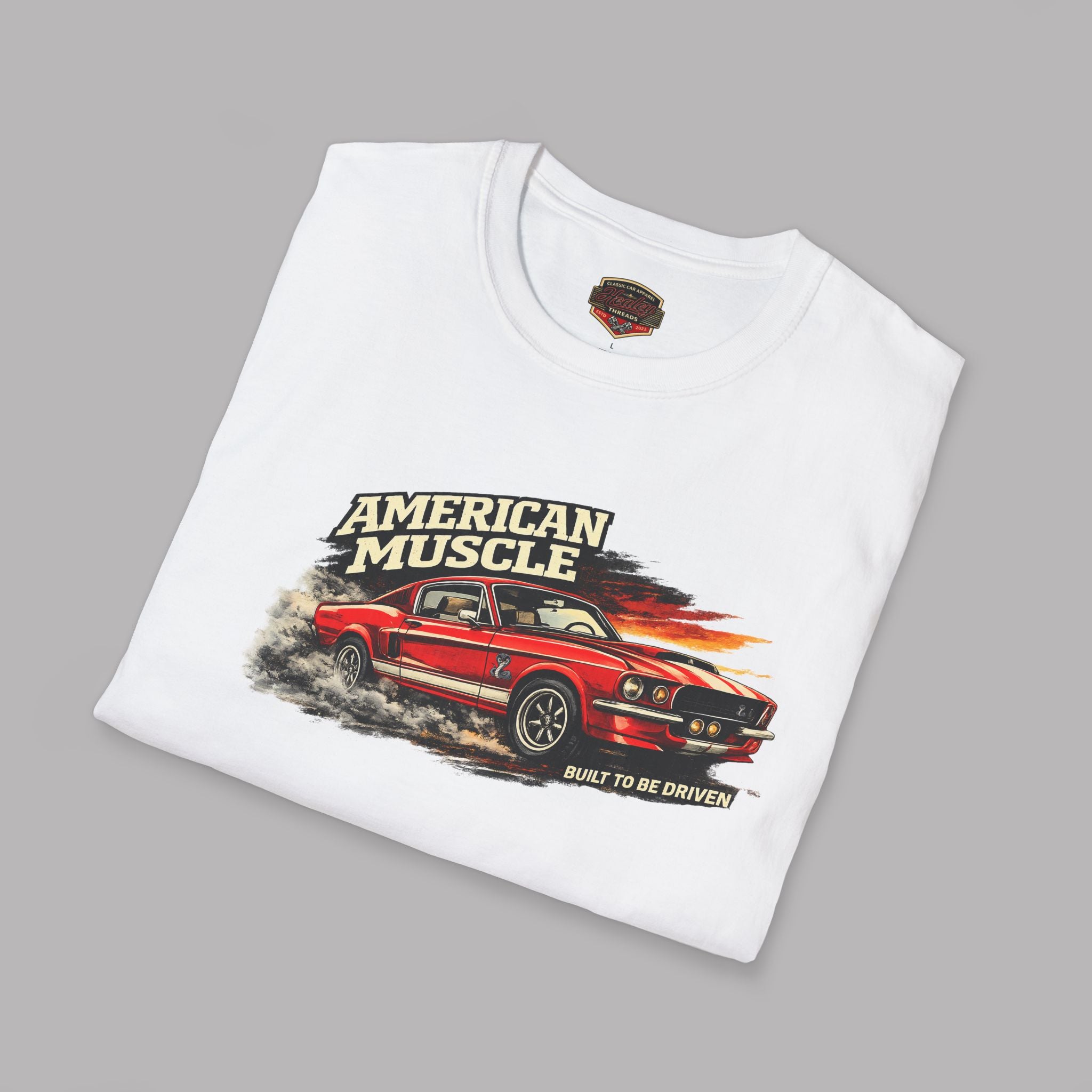 Folded white t-shirt with red car graphic and 'American Muscle' text on a gray background