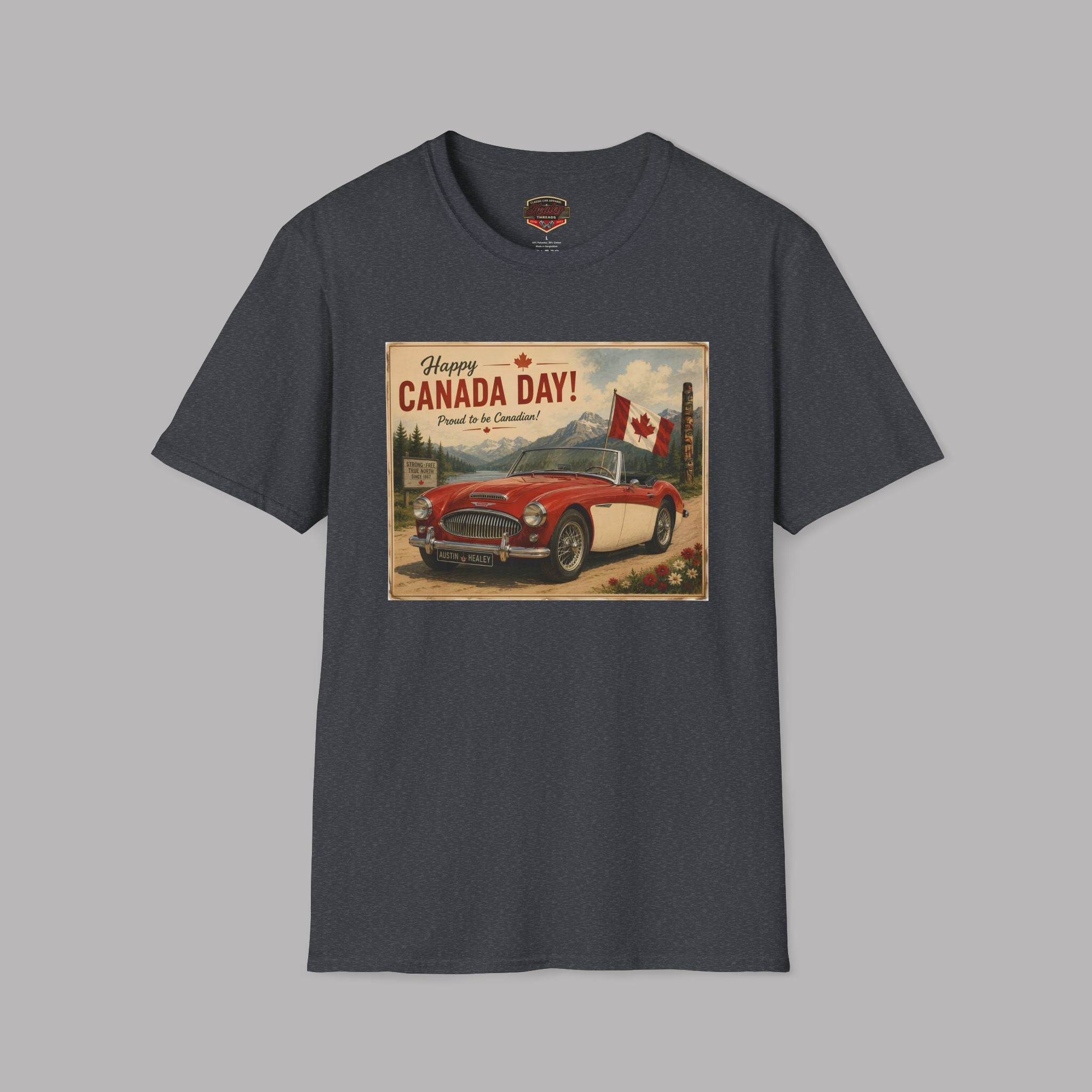 A dark gray crewneck t-shirt featuring a vintage-style Canada Day graphic print on the front, showing a red convertible car and a Canadian flag, displayed against a solid gray background.