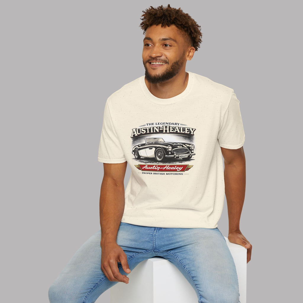 Man wearing a white t-shirt with Austin-Healey logo sitting on a white stool against a gray background