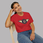 Woman wearing a Austin Healey winged badge logo with navy and gold circular emblem, heraldic shield, and cream wings on a red t-shirt flat on gray background