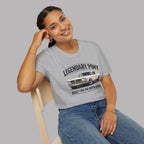 Woman wearing a gray t-shirt with a classic car graphic and text, sitting on a chair against a plain background
