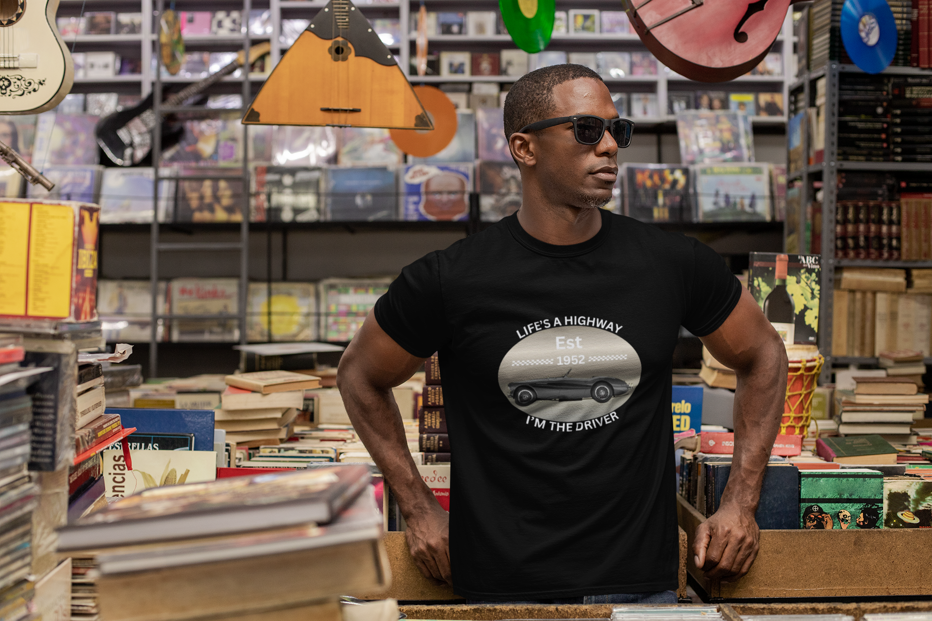 Man wearing a black t-shirt with a graphic design in a store with books and musical instruments.