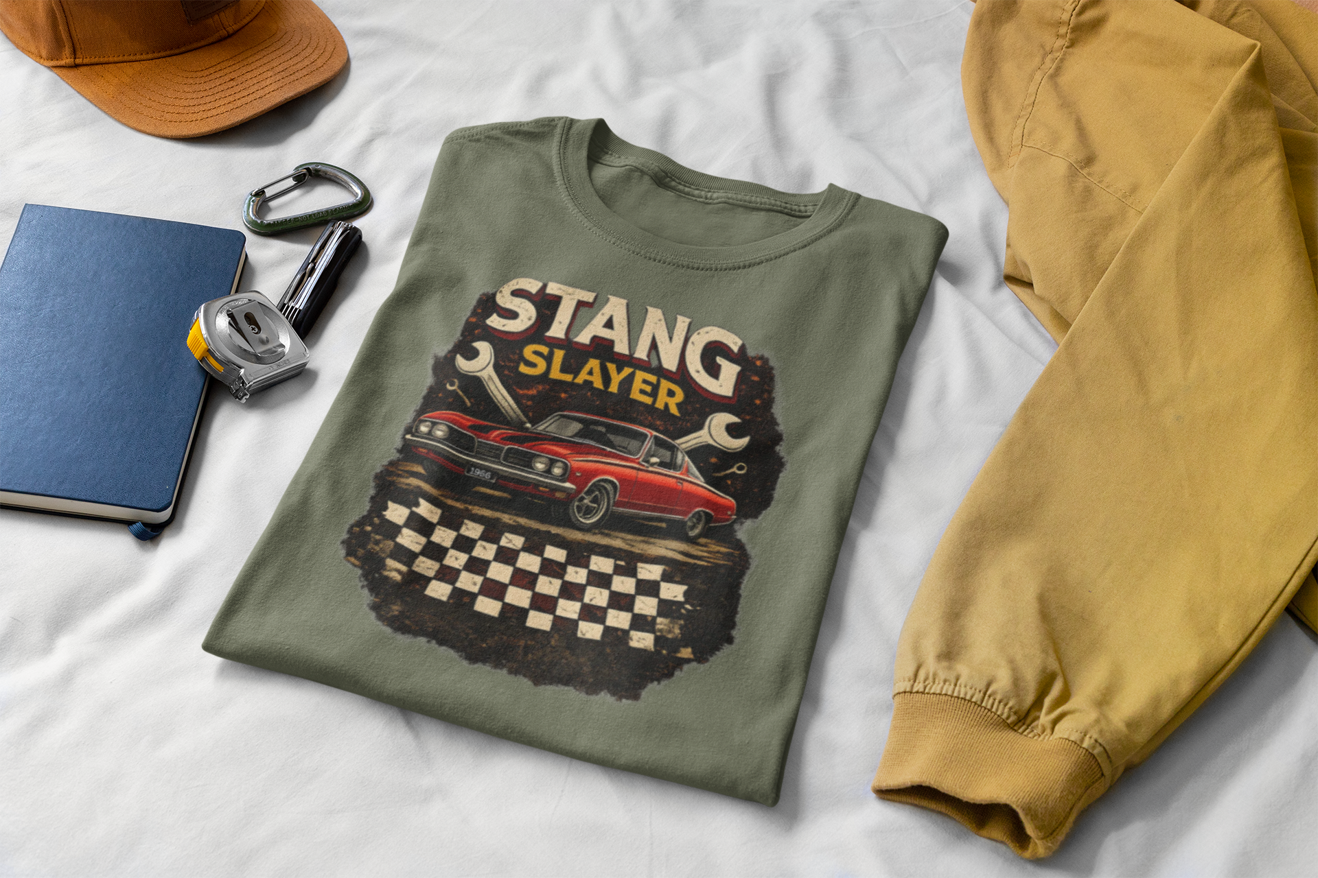 Military green t-shirt with 'STANG SLAYER' graphic on a white surface with accessories.