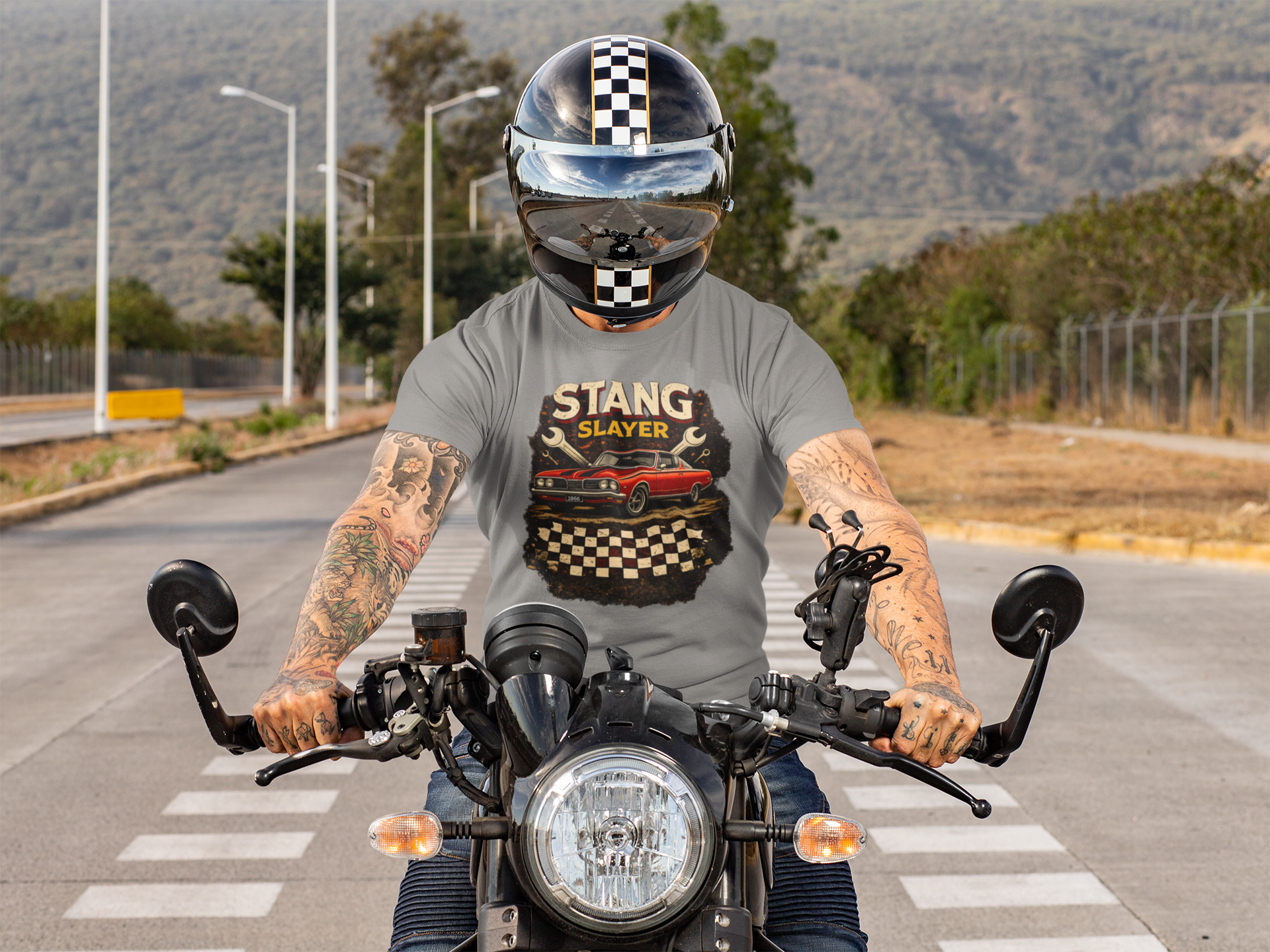 Person riding a motorcycle wearing a helmet and a t-shirt with 'STANG SLAYER' design.