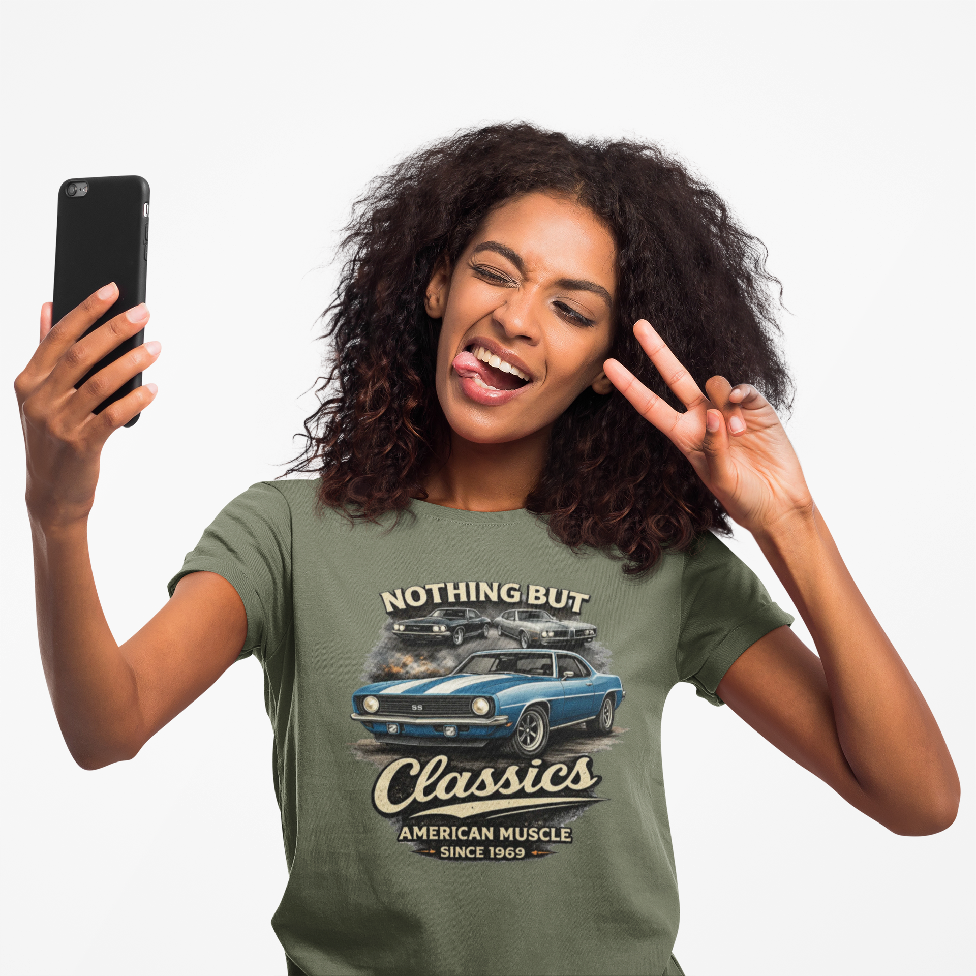 Woman wearing a military green t-shirt with a car graphic and text, taking a selfie.