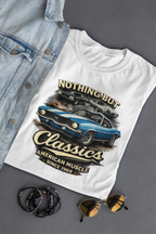 White t-shirt with car graphic and text on a gray surface with denim jacket, sunglasses, and bracelets.