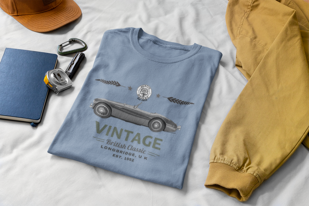 Blue t-shirt with vintage car design on a white surface with accessories.