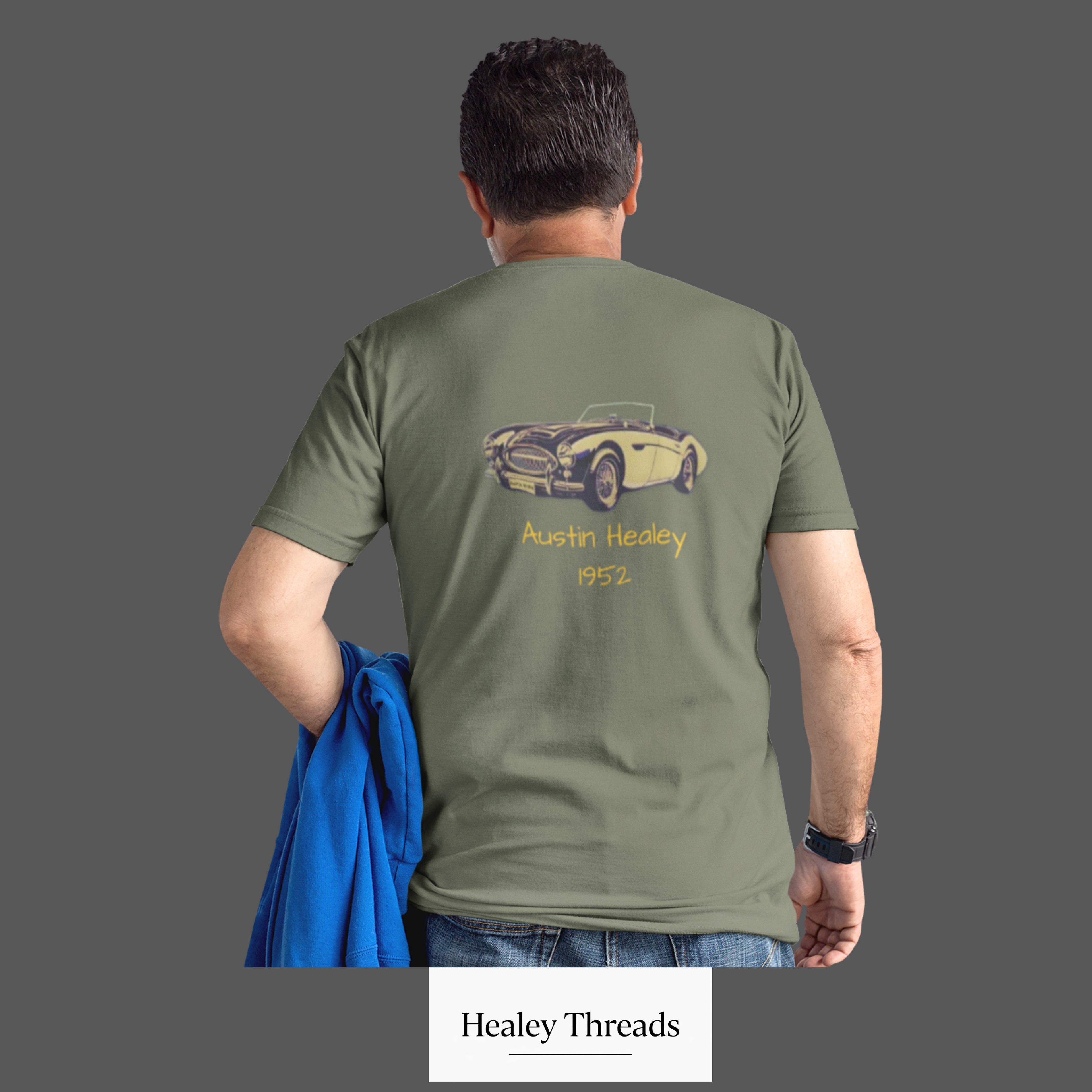 Back view of a man wearing a military green t-shirt with a vintage car design and 'Healey Threads' branding.