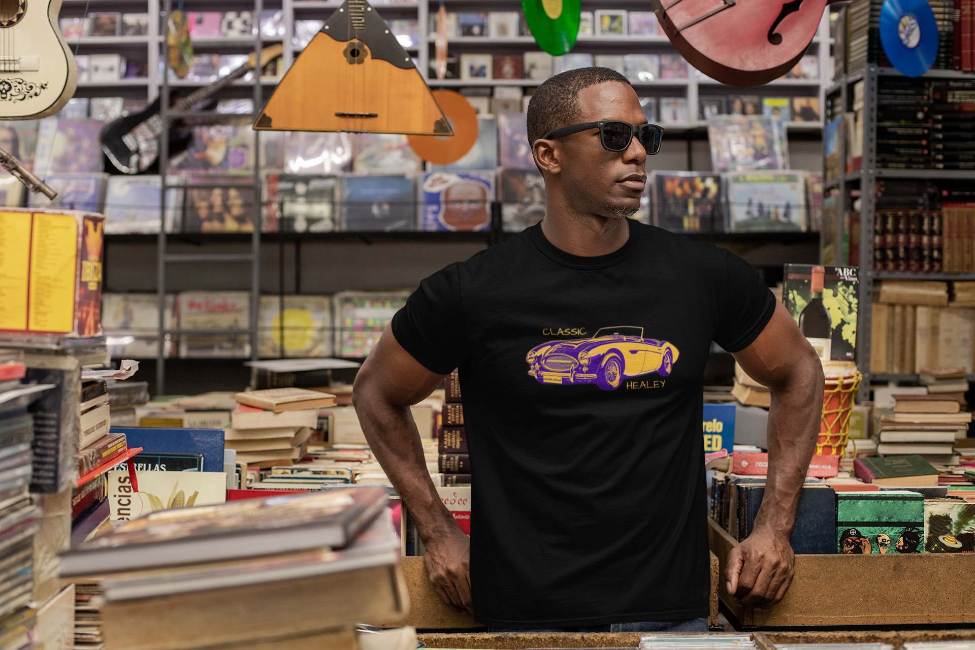 Man wearing a black t-shirt with a graphic design in a store with books and musical instruments.