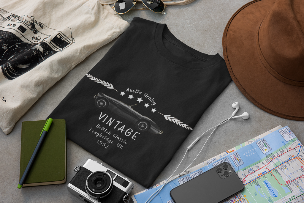 Black t-shirt with vintage camera design on a gray surface with accessories.