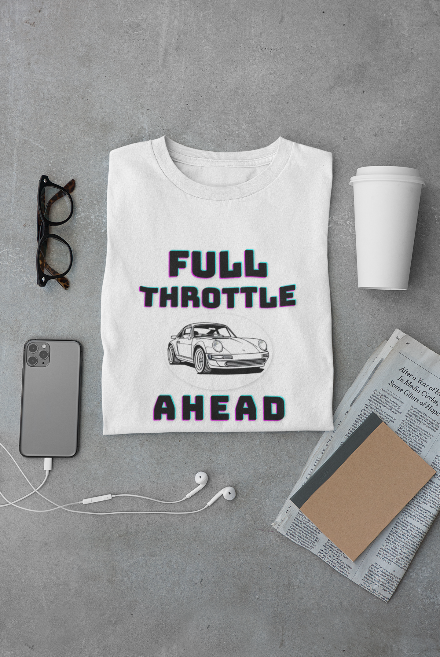 White t-shirt with 'Full Throttle Ahead' graphic on a gray surface with a phone, cup, and glasses.