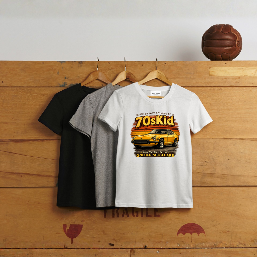 Three t-shirts on hangers; the front white shirt shows a vintage yellow car with the text “70s Kid – Born Too Late for the Golden Age of Cars.”