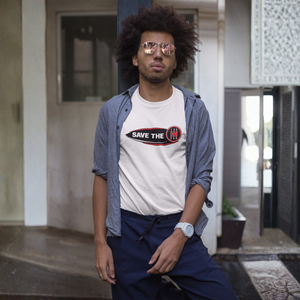 Man wearing a white t-shirt with 'Save the stick shift' graphic design leaning against a pole.