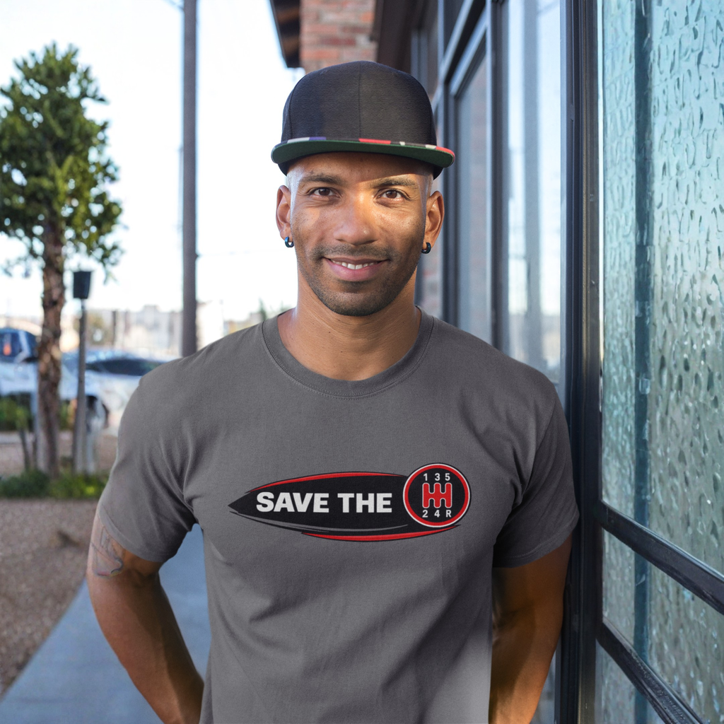 Man wearing a grey t-shirt leaning against a wall with 'Save the stick shift' graphic design 
