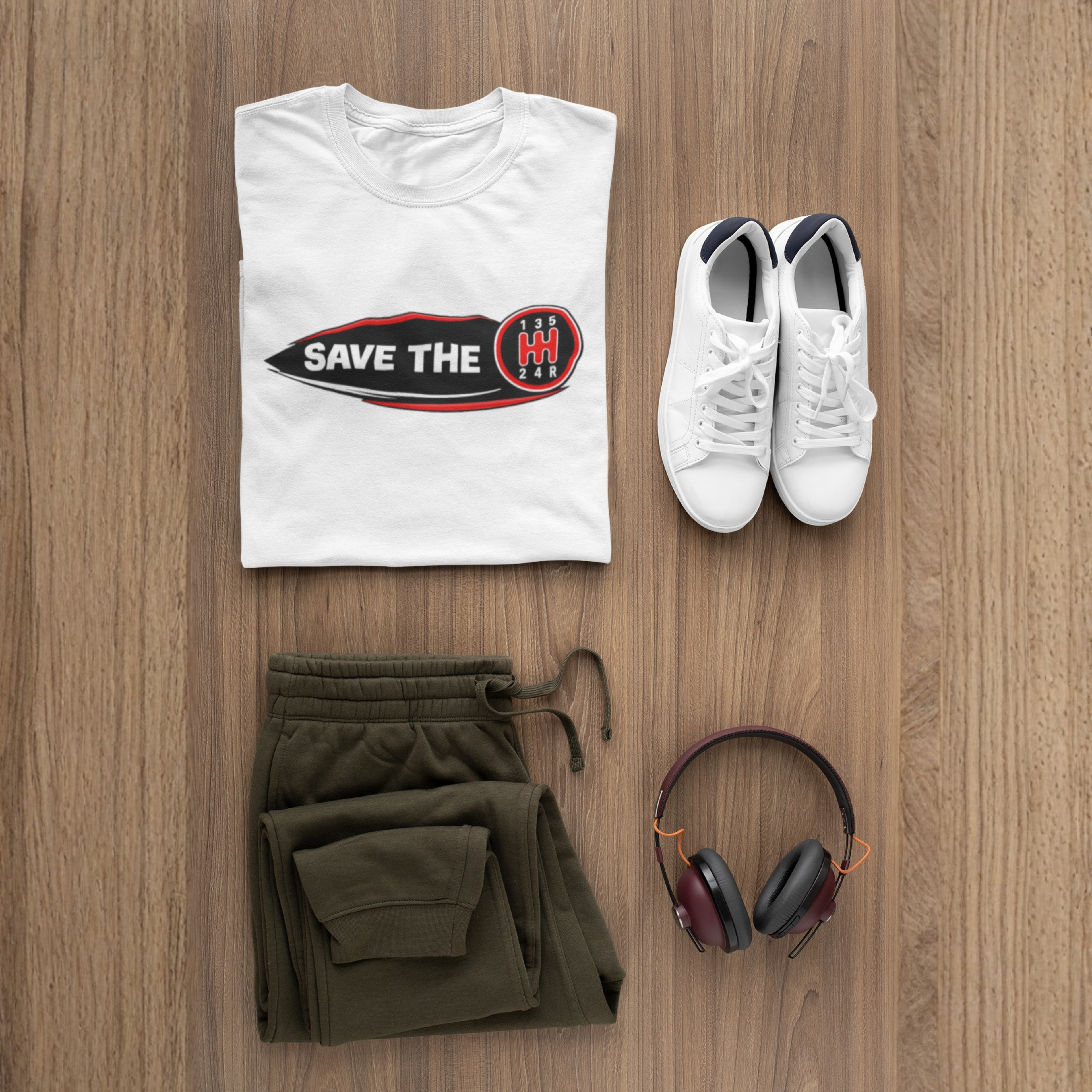  A white t-shirt with 'Save the stick shift' graphic design mockup with pants,shoes and headphones displayed.