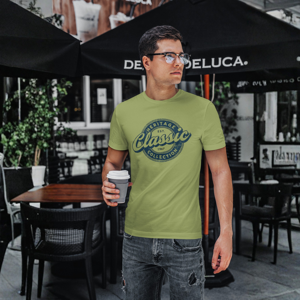 Man wearing a military green t-shirt with 'Heritage Classic Collection' design, holding a coffee cup outdoors.