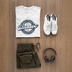 White t-shirt with blue graphic, white sneakers, green pants, and headphones on a wooden surface