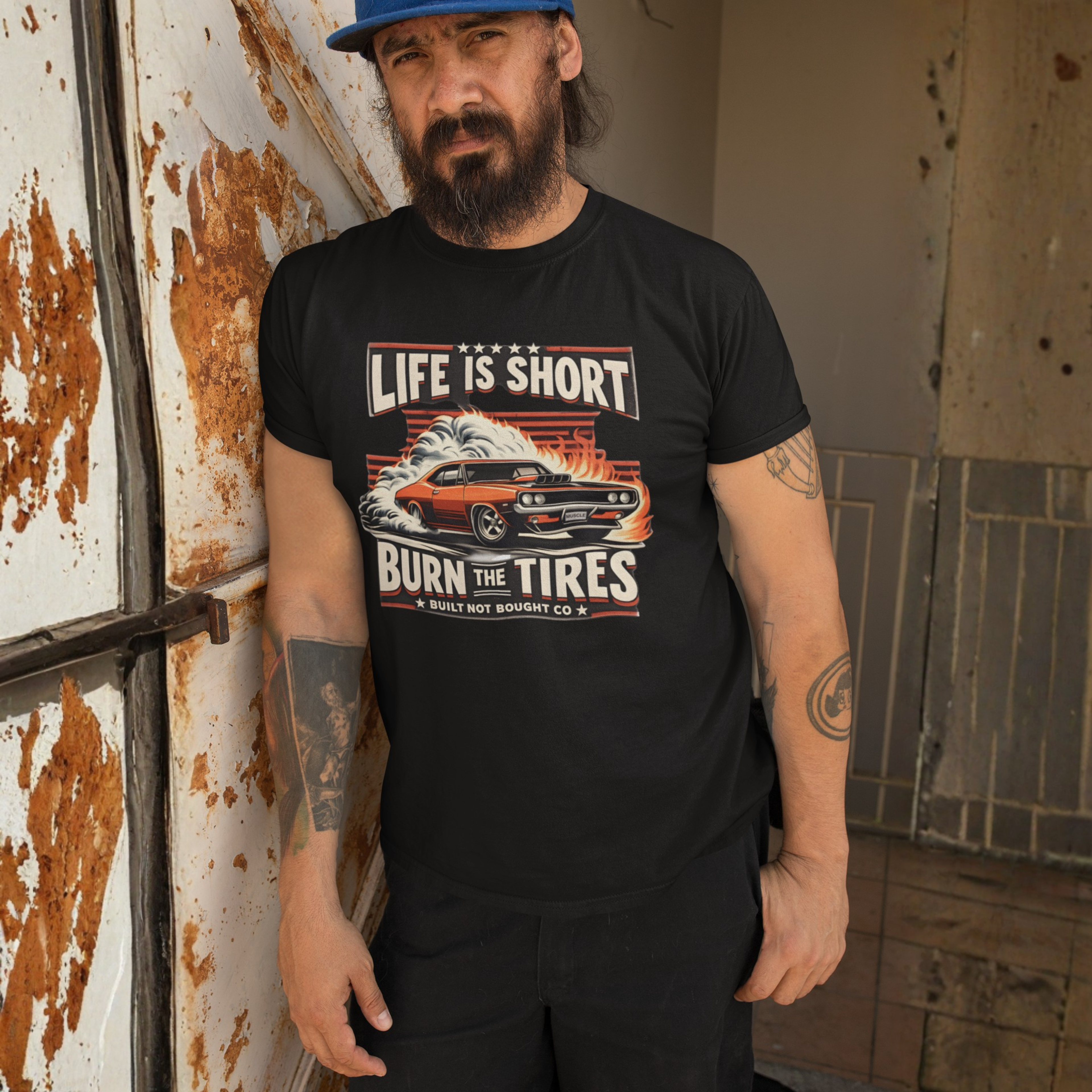 Man wearing a black t-shirt with a graphic design and text, standing in an industrial setting.