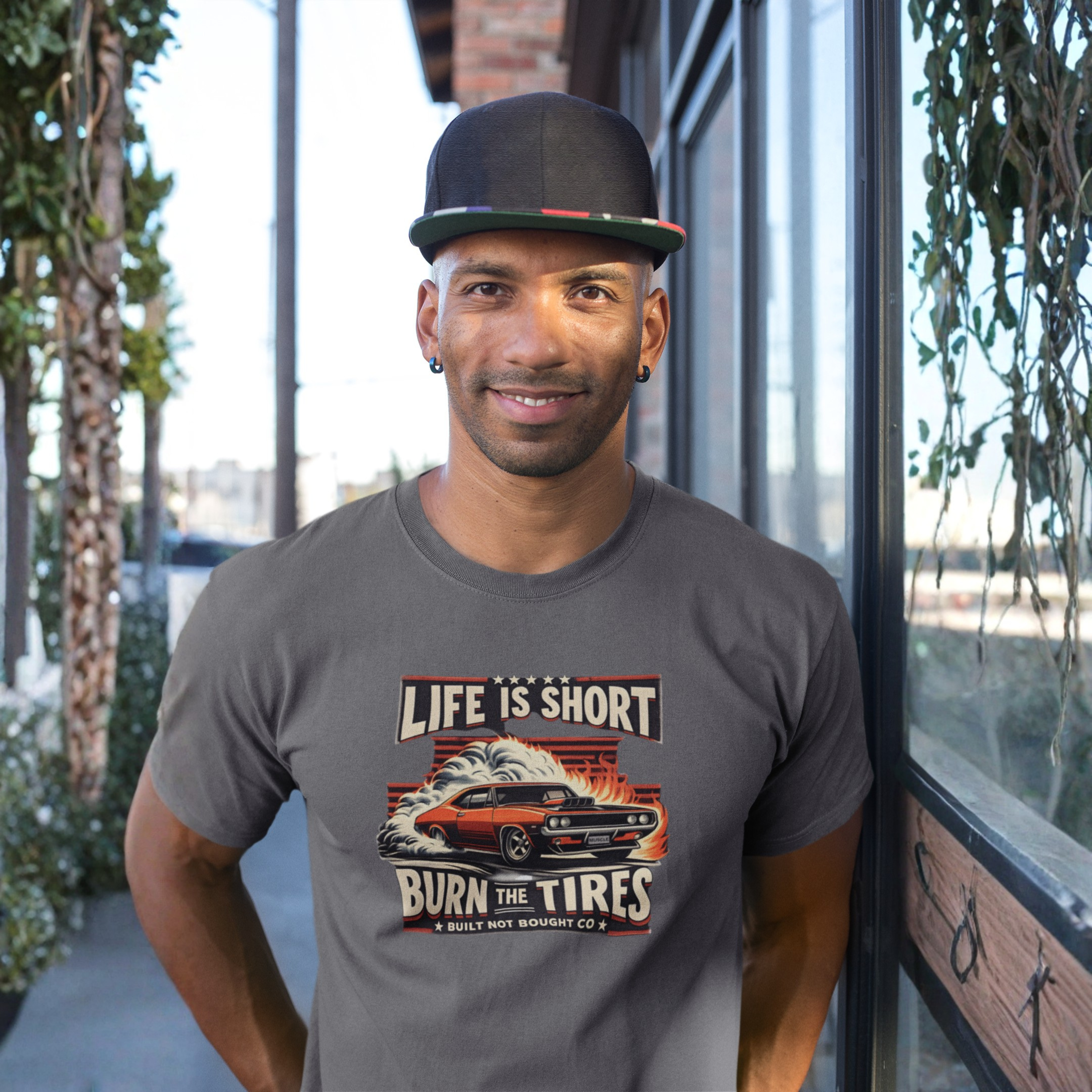 Man wearing a gray t-shirt with a graphic design and text, standing outdoors.