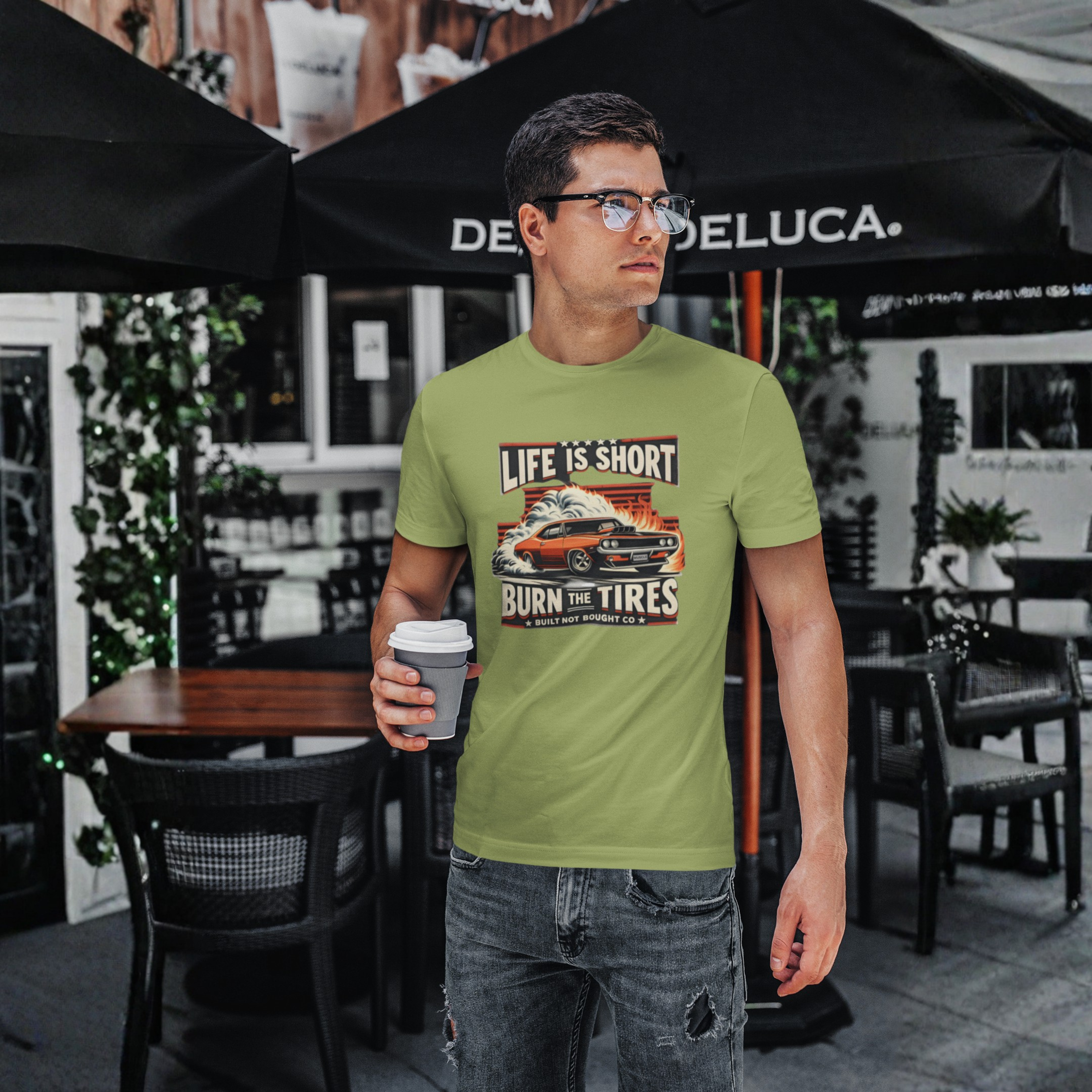 Man wearing a military green t-shirt with a graphic design, standing under a Deluca umbrella.