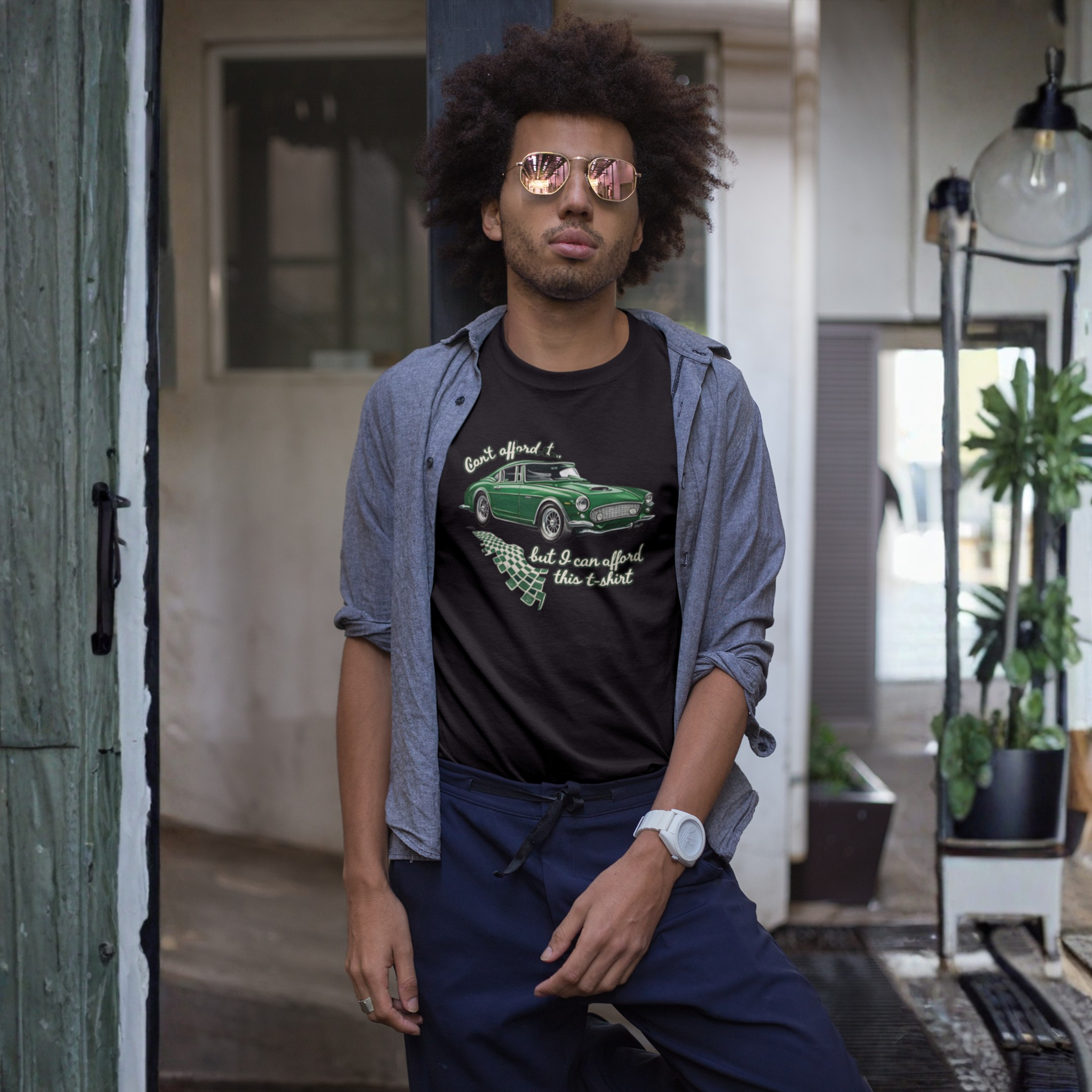 Man wearing sunglasses and a graphic t-shirt in an indoor setting with plants.