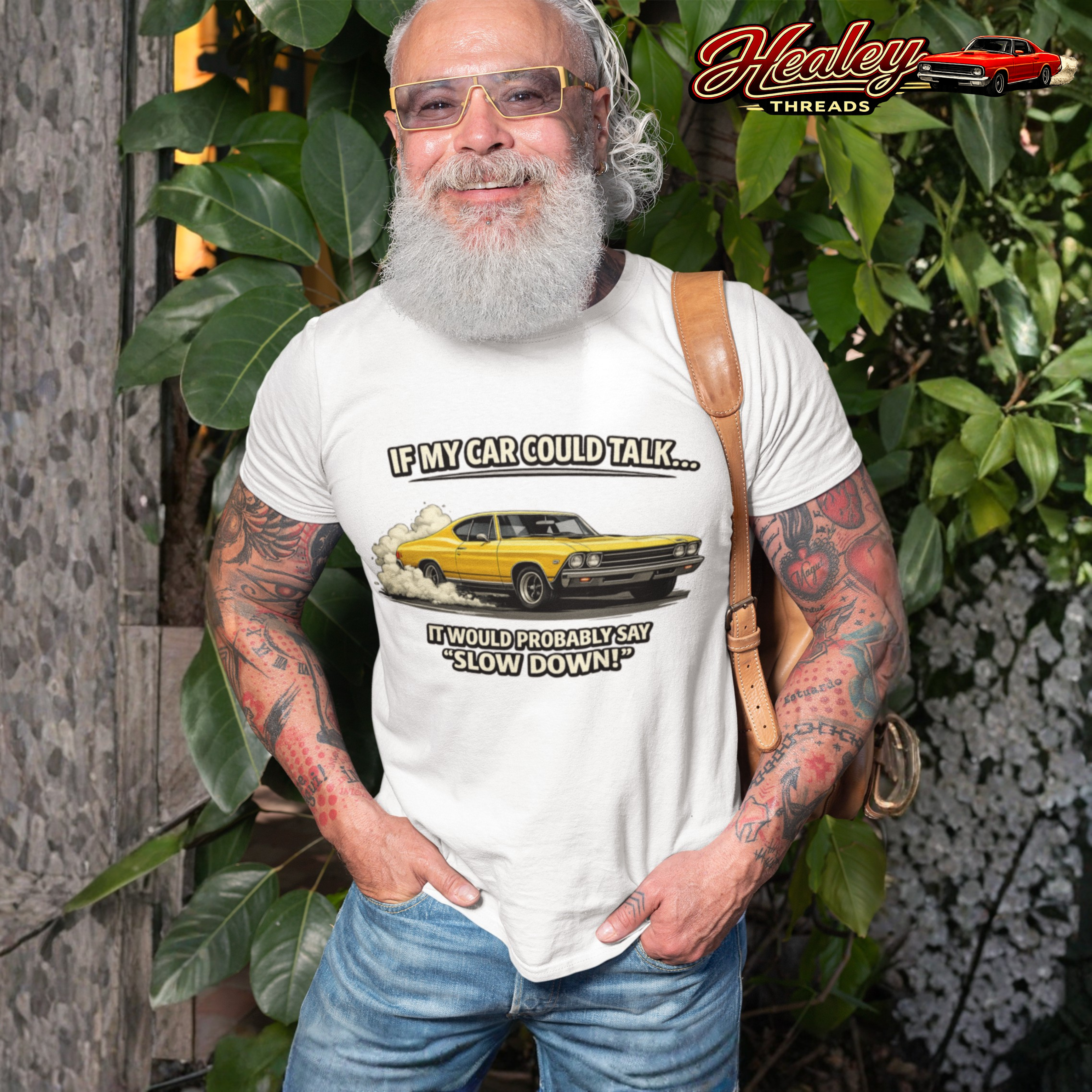 Man wearing a white t-shirt with a graphic and text, standing outdoors with greenery in the background.