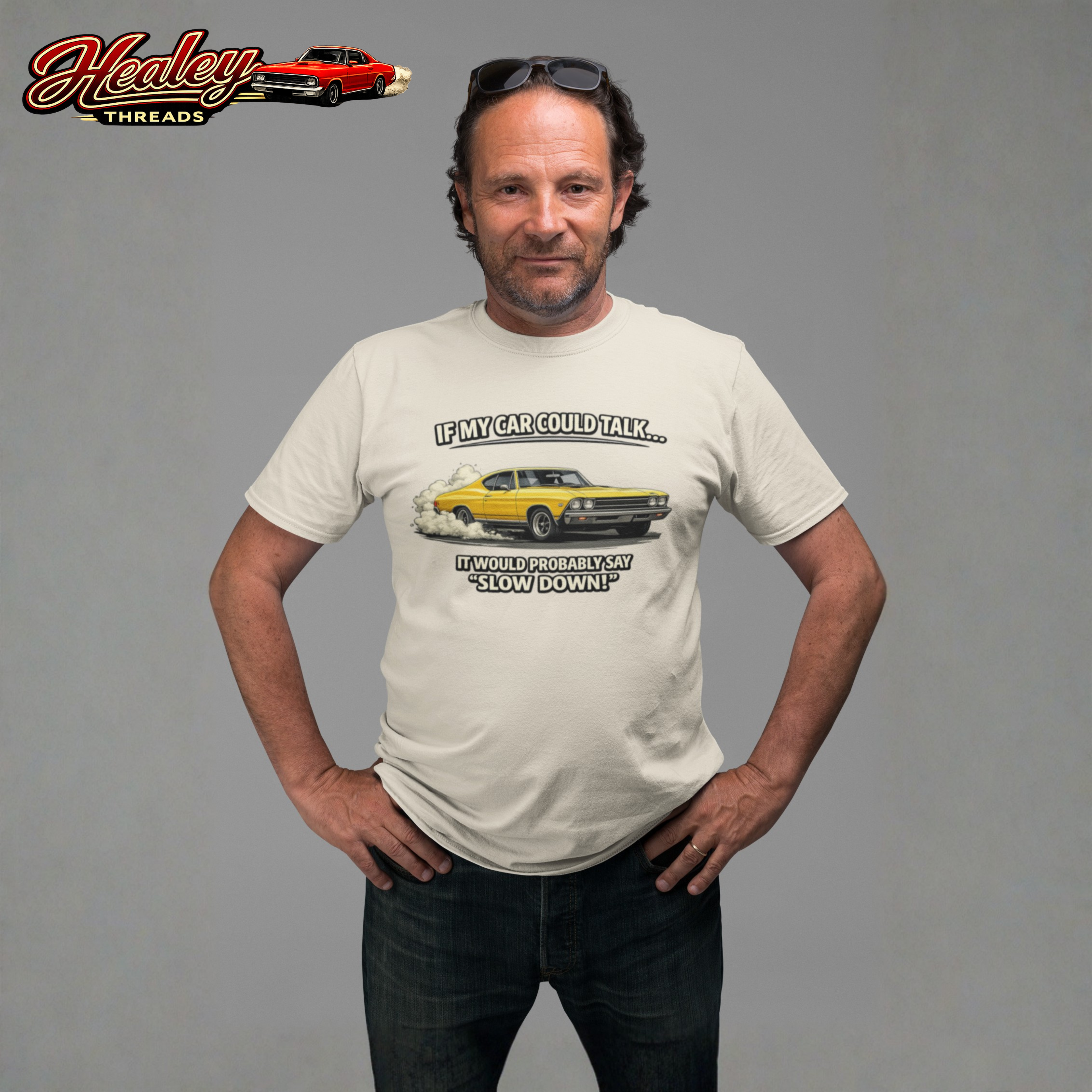 Man wearing a t-shirt with a car graphic and text, standing against a gray background with Healey Threads logo.