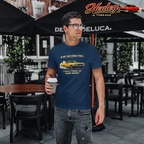 Man wearing a blue t-shirt with a graphic design, holding a coffee cup, standing in an outdoor setting.