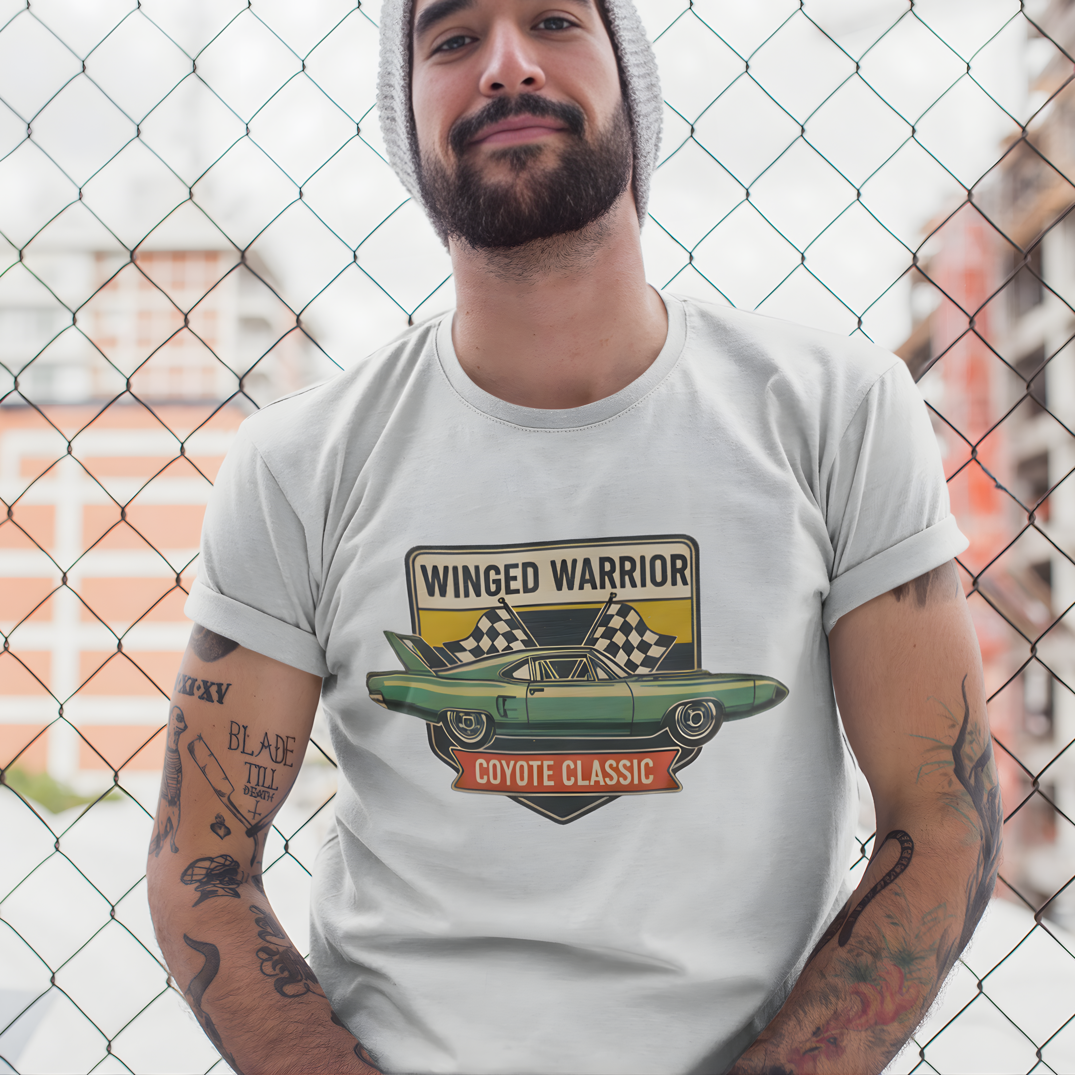 Man wearing a ash t-shirt with a 'Winged Warrior Coyote Classic' graphic design in front of a chain-link fence.