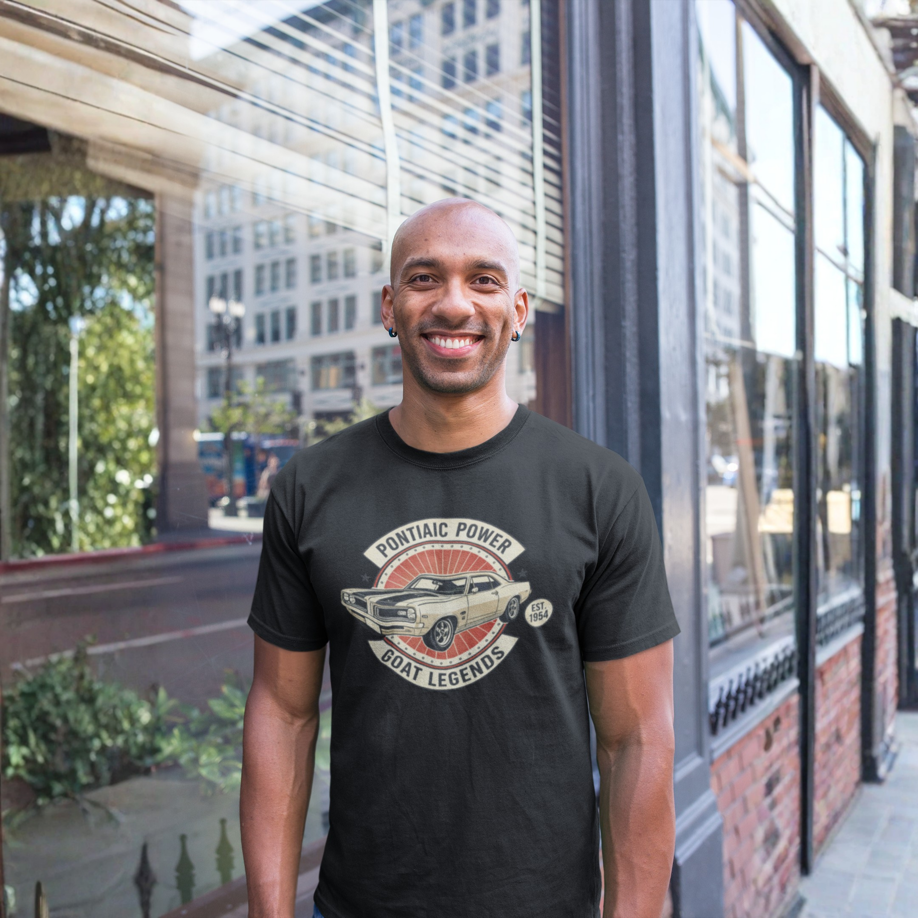 Man wearing a black t-shirt with a graphic design standing in front of a glass building.