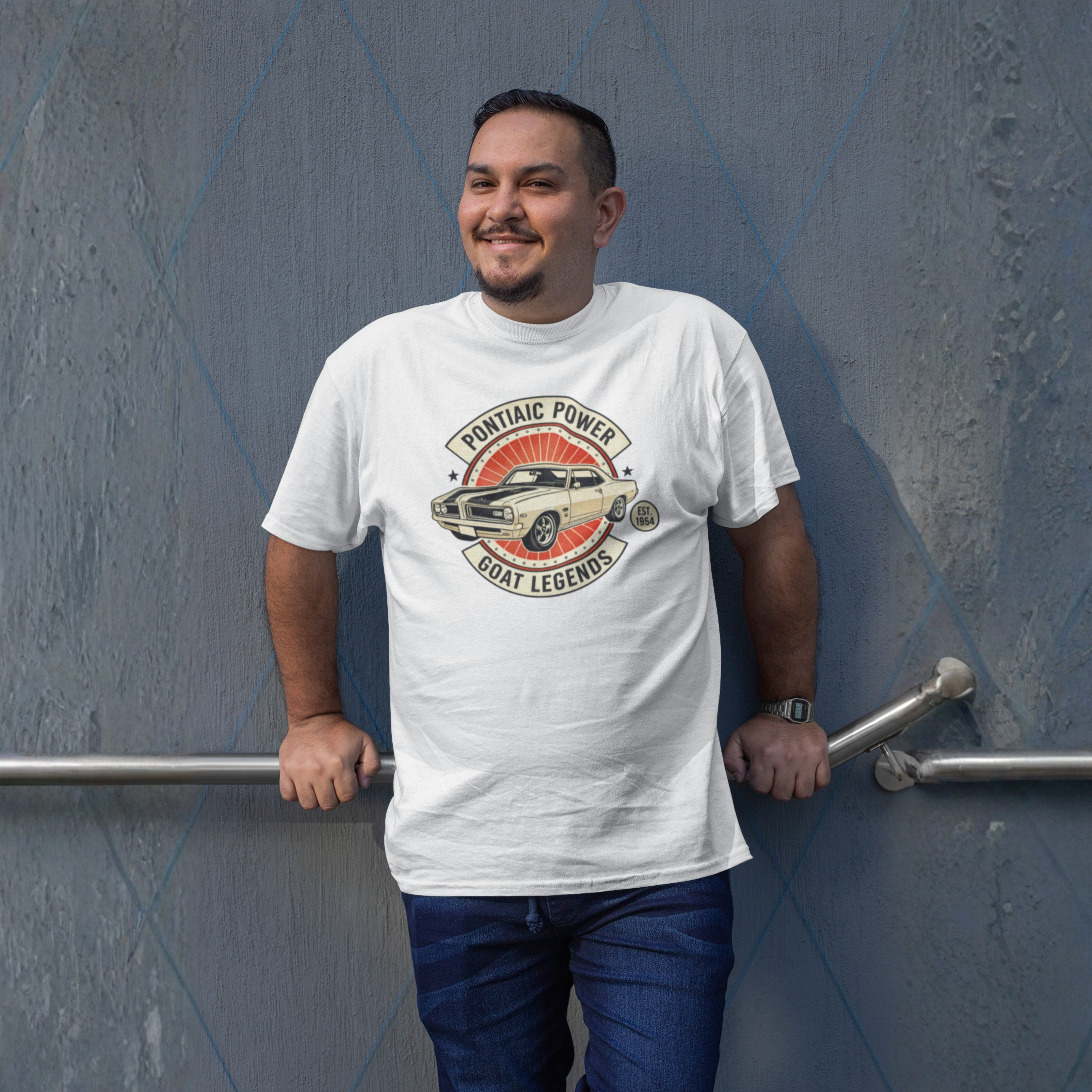 Man wearing a white t-shirt with a graphic design against a gray wall.