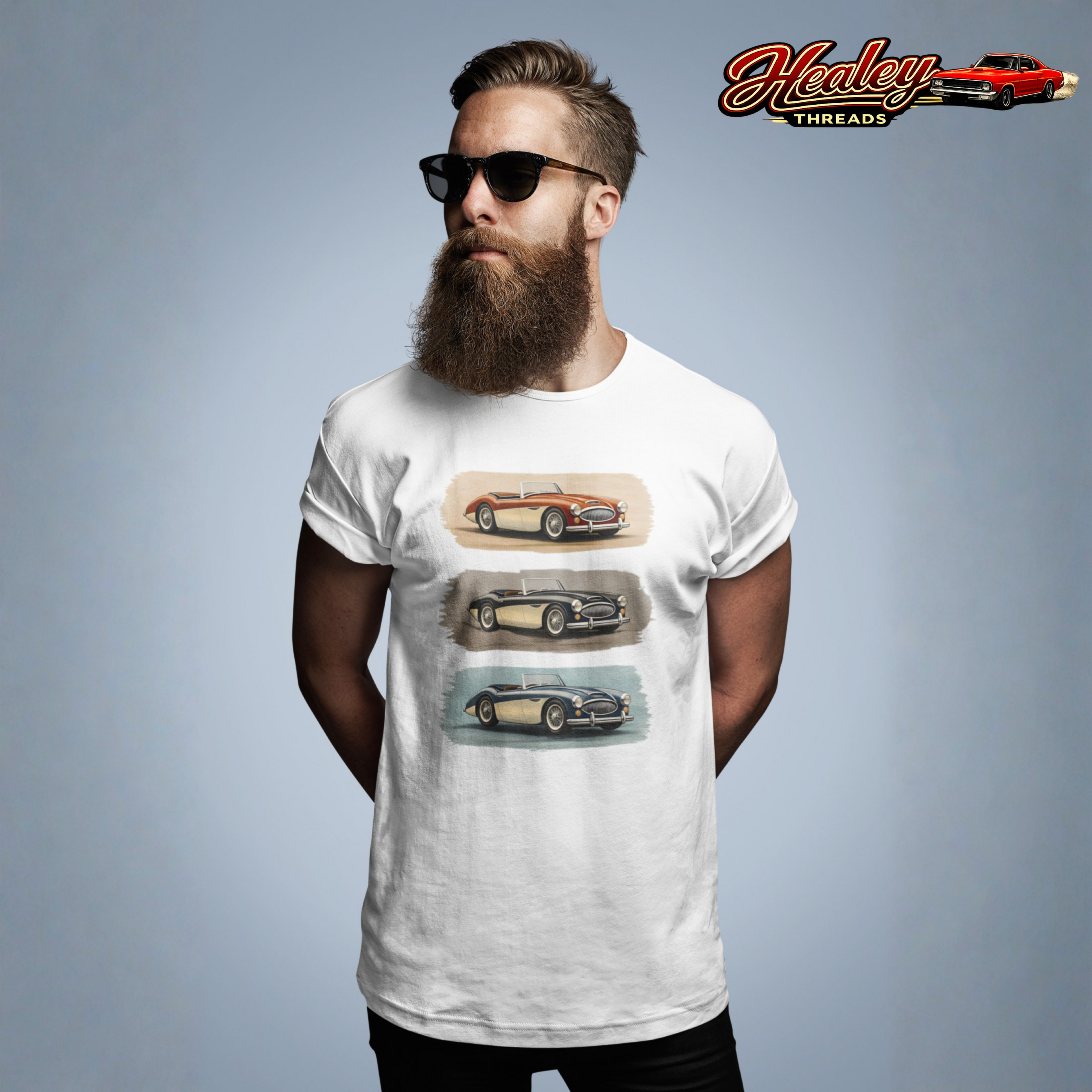 Man wearing a white Healey t-shirt with car graphics and sunglasses, standing against a gray background with 'Healey Threads' logo.