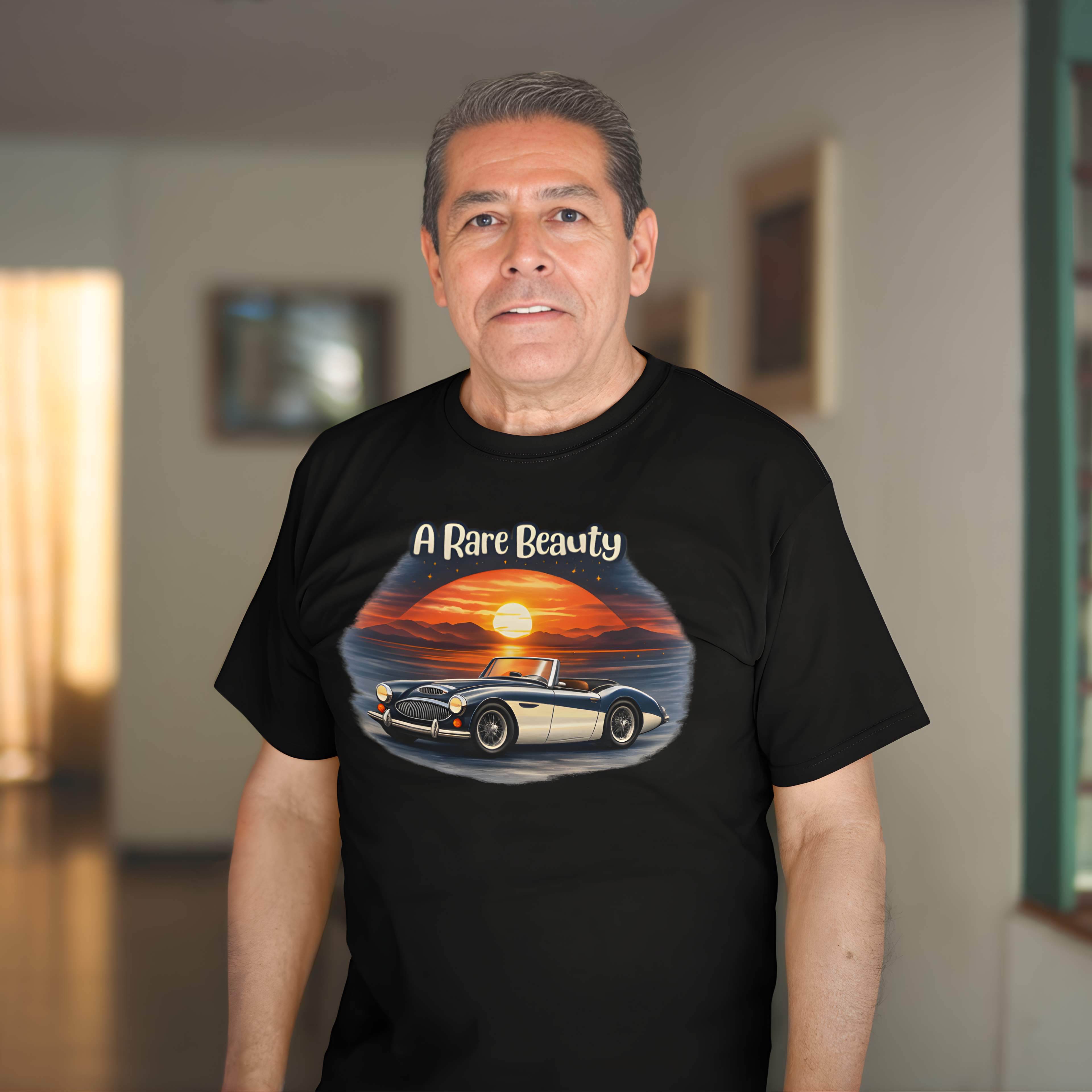 Man wearing a black t-shirt with a Healey graphic design of a car and sunset text 'A Rare Beauty'.